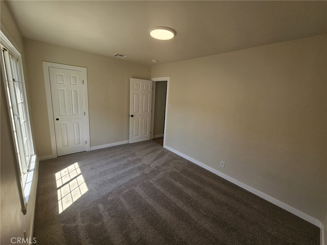 unfurnished bedroom featuring dark carpet and a closet