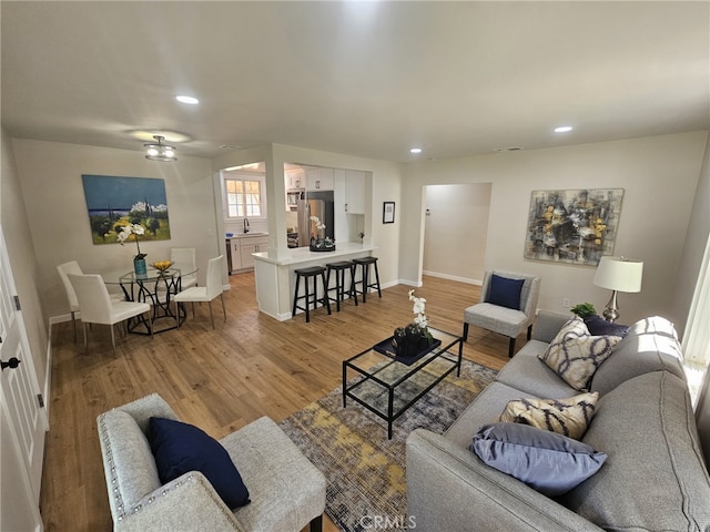 living room featuring light hardwood / wood-style floors, ceiling fan, and sink