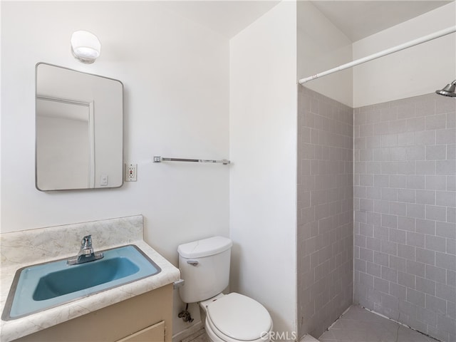 bathroom with a tile shower, vanity, and toilet