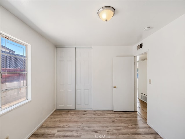 unfurnished bedroom with light hardwood / wood-style flooring and a closet