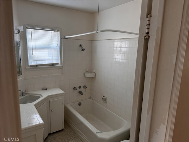 bathroom with tiled shower / bath combo, tile patterned flooring, and vanity