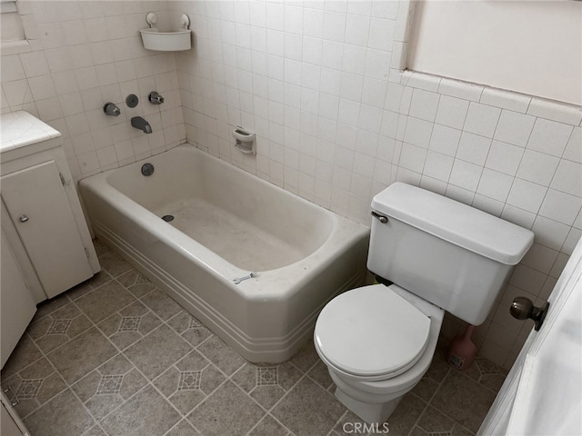 bathroom featuring tile walls, tile patterned flooring, a bathtub, vanity, and toilet