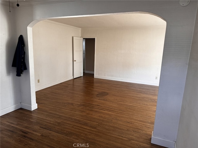 empty room featuring ornamental molding and dark wood-type flooring