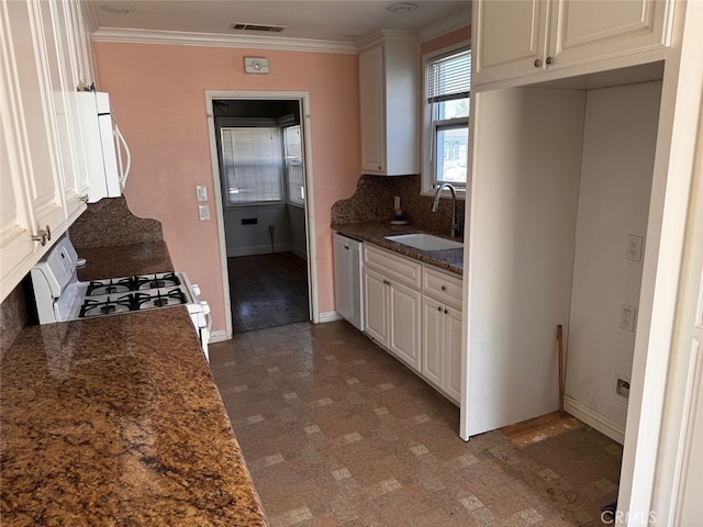 kitchen with white cabinets, ornamental molding, sink, white appliances, and dark stone countertops