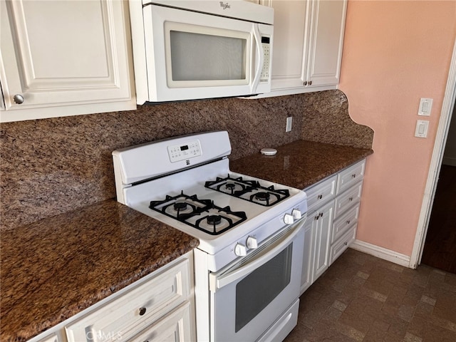 kitchen featuring dark stone counters, white cabinets, and white appliances