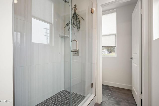 bathroom featuring tile patterned flooring, a stall shower, and baseboards