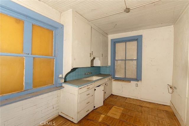 kitchen featuring white cabinets, light parquet flooring, tasteful backsplash, and sink