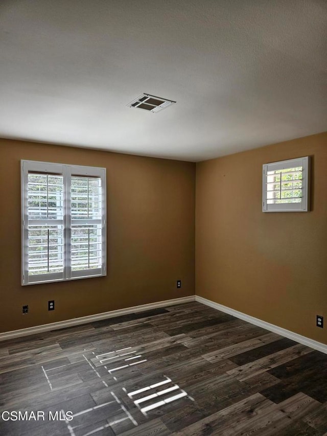 spare room featuring plenty of natural light and dark hardwood / wood-style flooring