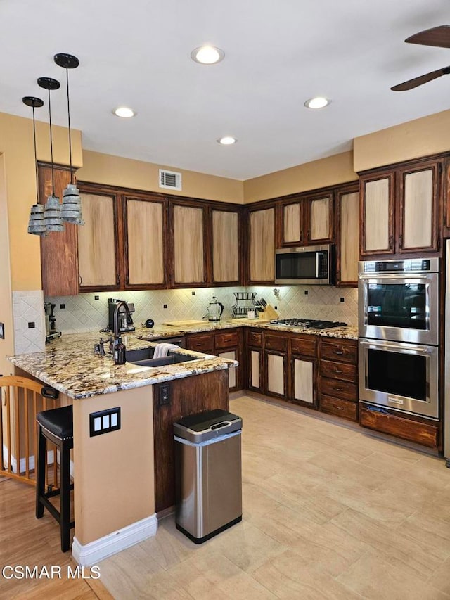 kitchen featuring ceiling fan, hanging light fixtures, sink, kitchen peninsula, and stainless steel appliances