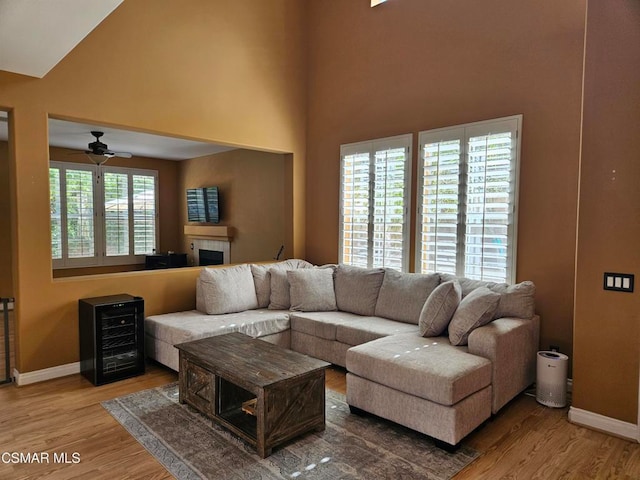 living room with a high ceiling, light hardwood / wood-style floors, ceiling fan, and wine cooler