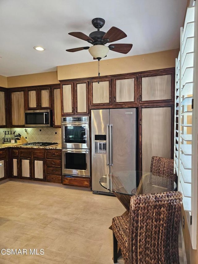 kitchen with stainless steel appliances, backsplash, ceiling fan, and dark brown cabinetry