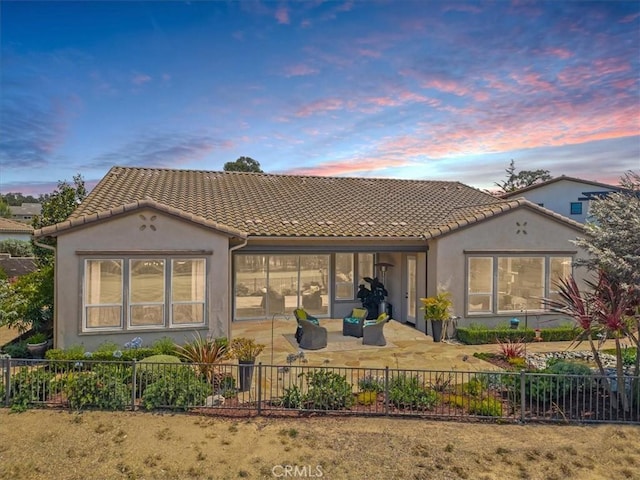 rear view of property with a patio, a tile roof, fence private yard, outdoor lounge area, and stucco siding