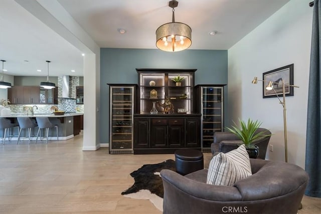 living room featuring light wood-style floors, recessed lighting, beverage cooler, and baseboards