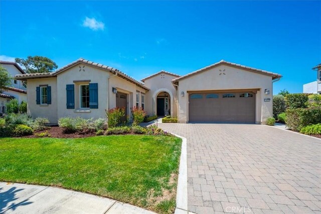 mediterranean / spanish-style home featuring a front lawn and a garage