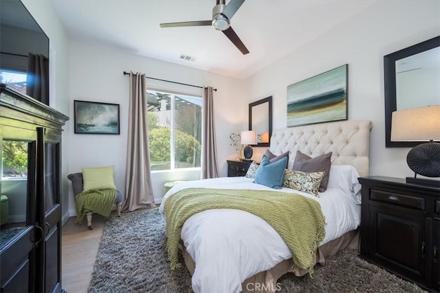 bedroom featuring a ceiling fan, visible vents, and wood finished floors