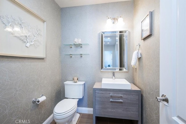 bathroom featuring toilet, baseboards, and vanity