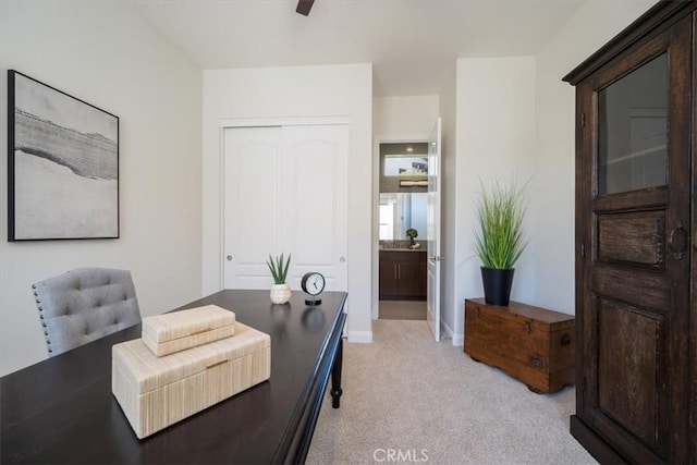 office area with a ceiling fan, light carpet, and baseboards