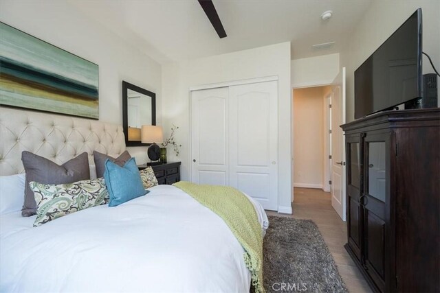 bedroom with a ceiling fan, a closet, baseboards, and wood finished floors