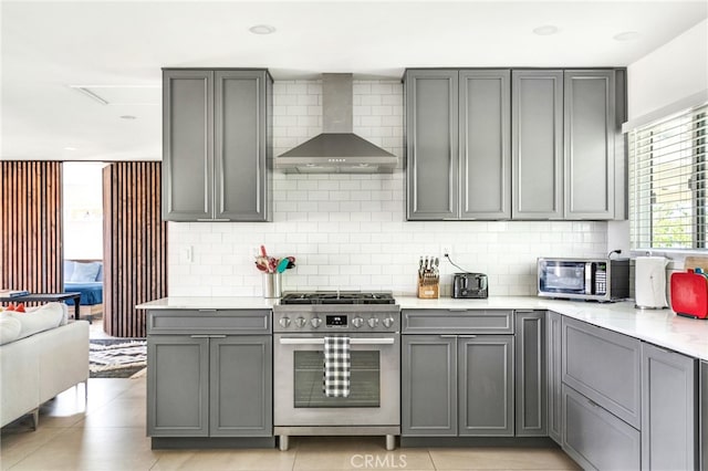 kitchen featuring gray cabinetry, stainless steel appliances, and wall chimney exhaust hood