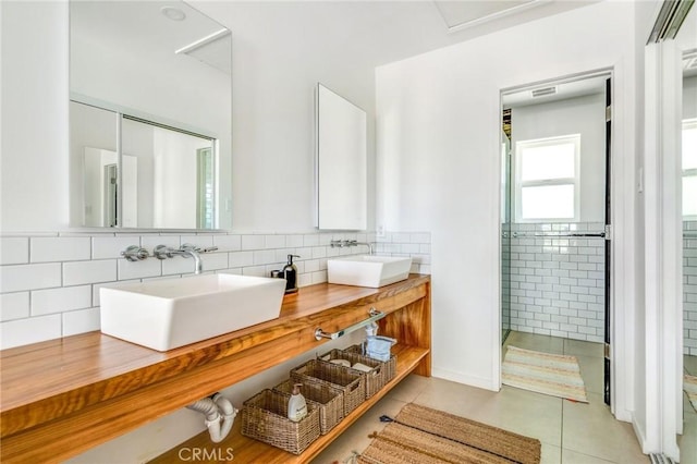 bathroom with tile patterned floors, a sink, double vanity, and tiled shower