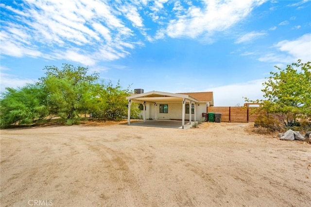 back of house featuring fence, an attached carport, and stucco siding