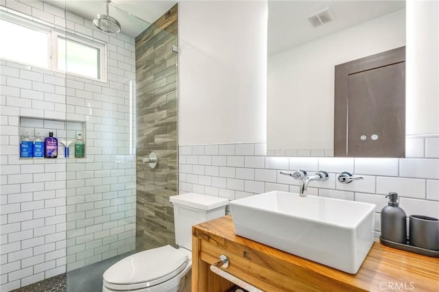 bathroom featuring vanity, tile walls, walk in shower, toilet, and visible vents