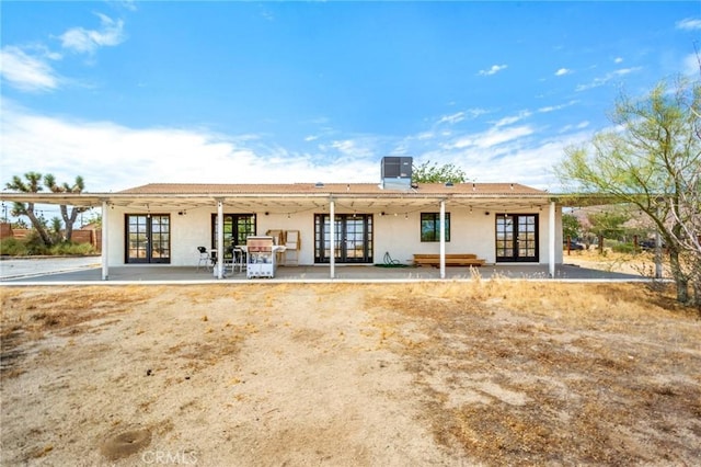 rear view of house with stucco siding, central air condition unit, a patio area, and french doors