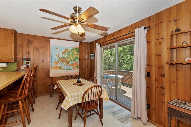 dining area with a textured ceiling, ceiling fan, and wooden walls