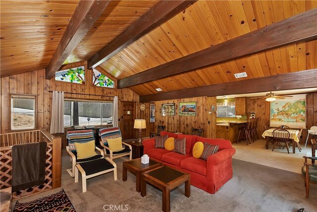 carpeted living room with ceiling fan, wood walls, vaulted ceiling with beams, and wooden ceiling