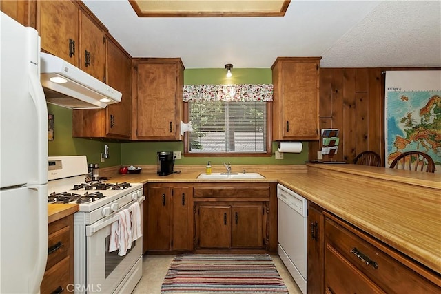 kitchen with sink, white appliances, and wooden walls