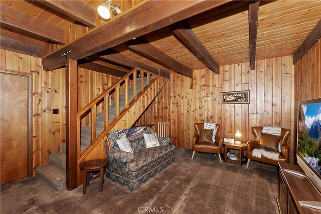 unfurnished room with wood ceiling, carpet, beamed ceiling, and wooden walls