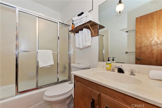 full bathroom with enclosed tub / shower combo, vanity, and toilet