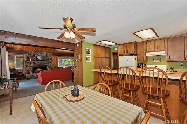 carpeted dining room with ceiling fan, a textured ceiling, and a fireplace