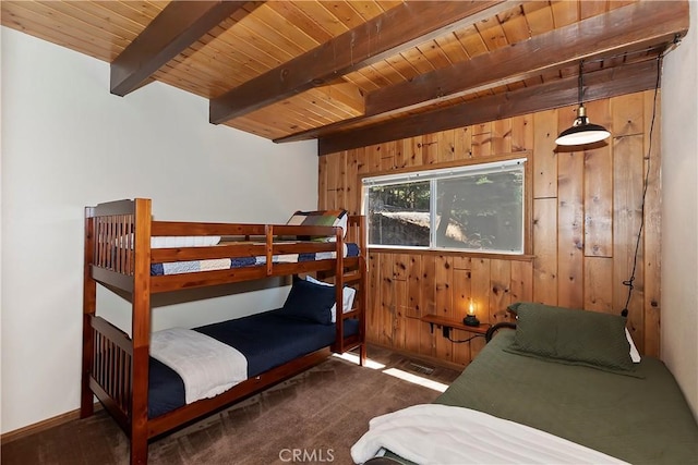 bedroom with wood walls, beam ceiling, wood ceiling, and dark colored carpet