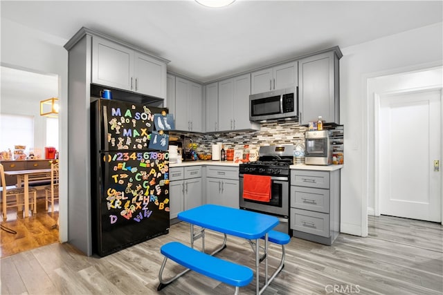 kitchen featuring backsplash, appliances with stainless steel finishes, light hardwood / wood-style flooring, and gray cabinets