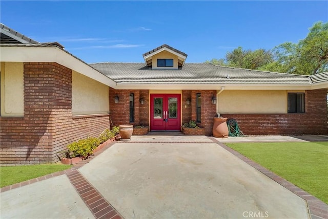 view of exterior entry with a lawn and french doors