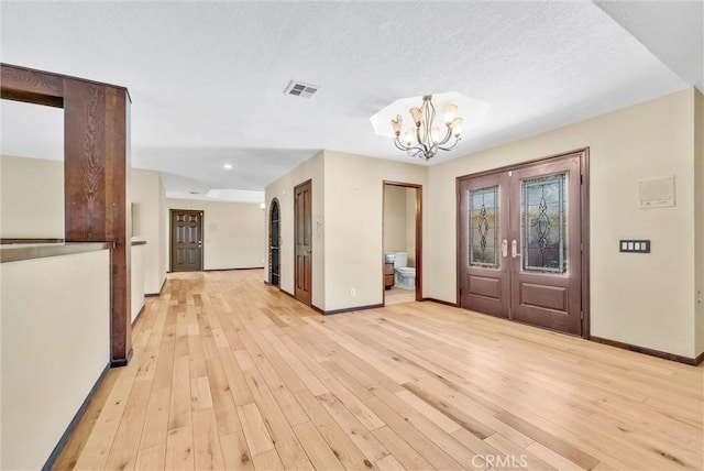 entrance foyer with a textured ceiling, an inviting chandelier, and light hardwood / wood-style flooring