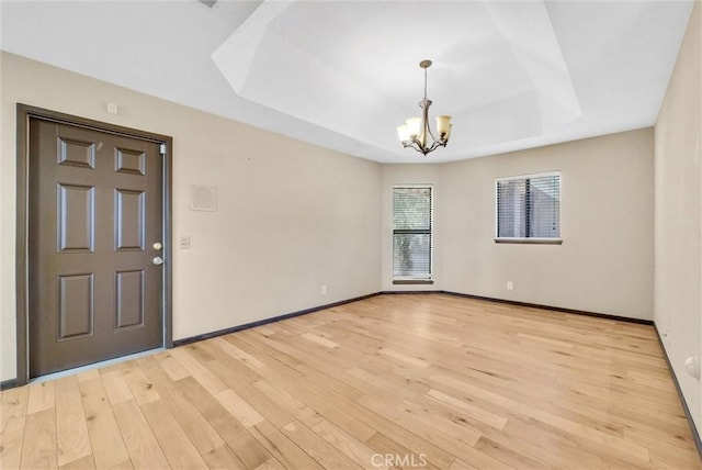 interior space featuring a tray ceiling, a chandelier, and light hardwood / wood-style floors