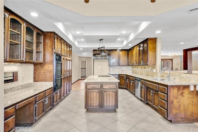 kitchen featuring a center island, a raised ceiling, sink, appliances with stainless steel finishes, and decorative light fixtures