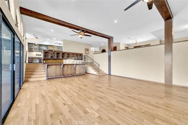 unfurnished living room featuring beam ceiling, light hardwood / wood-style floors, and ceiling fan