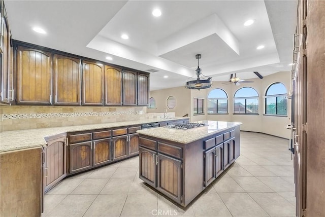 kitchen featuring tasteful backsplash, a raised ceiling, and a kitchen island