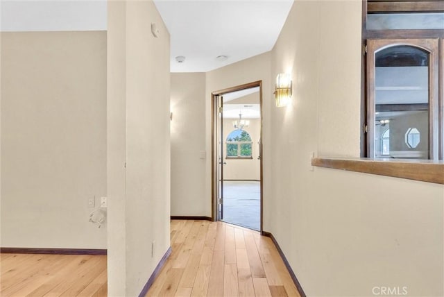 hallway featuring light hardwood / wood-style floors and an inviting chandelier