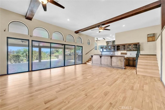 living room with a wealth of natural light, light hardwood / wood-style flooring, and beamed ceiling