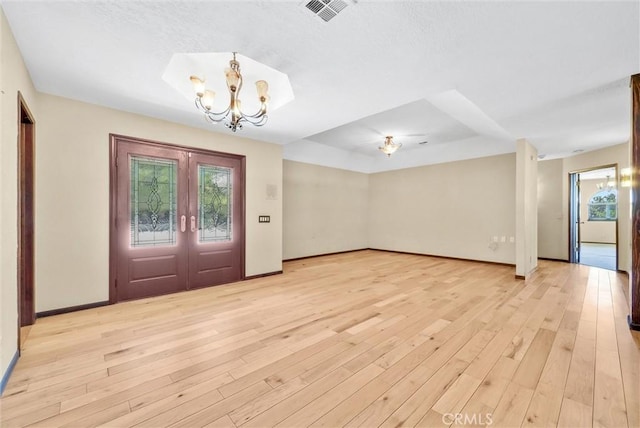 entrance foyer featuring light hardwood / wood-style flooring, french doors, and an inviting chandelier