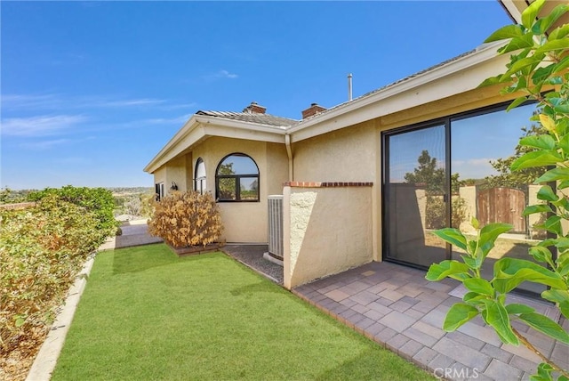 view of exterior entry featuring a yard and central AC