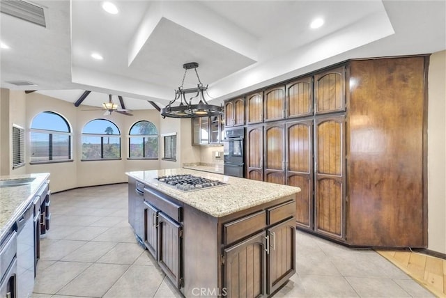 kitchen with appliances with stainless steel finishes, a raised ceiling, ceiling fan, pendant lighting, and a center island