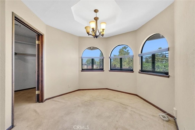 carpeted empty room with a healthy amount of sunlight and an inviting chandelier