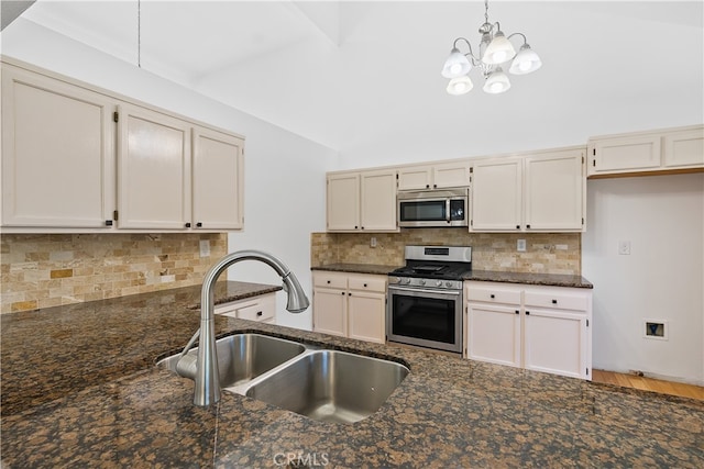 kitchen with appliances with stainless steel finishes, dark stone countertops, tasteful backsplash, an inviting chandelier, and sink