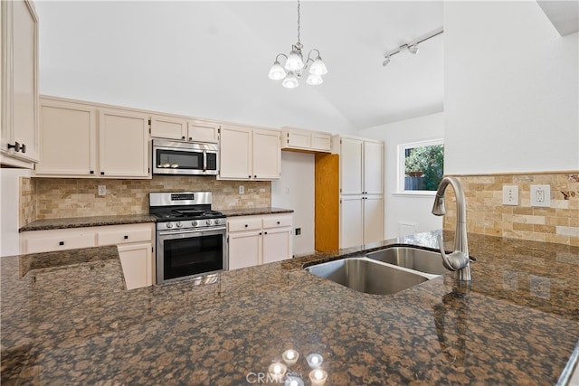 kitchen with dark stone counters, sink, a notable chandelier, stainless steel appliances, and backsplash