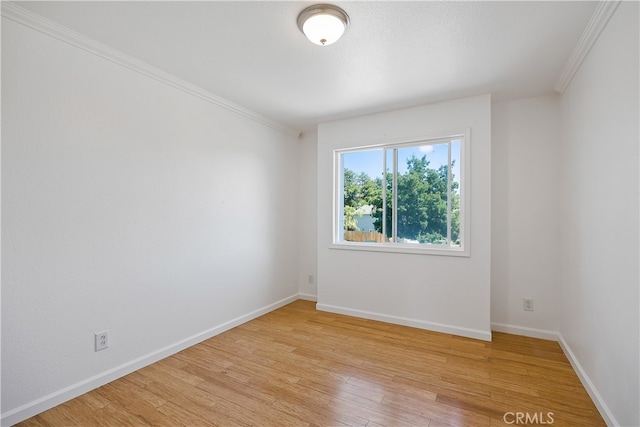 spare room with ornamental molding and light wood-type flooring